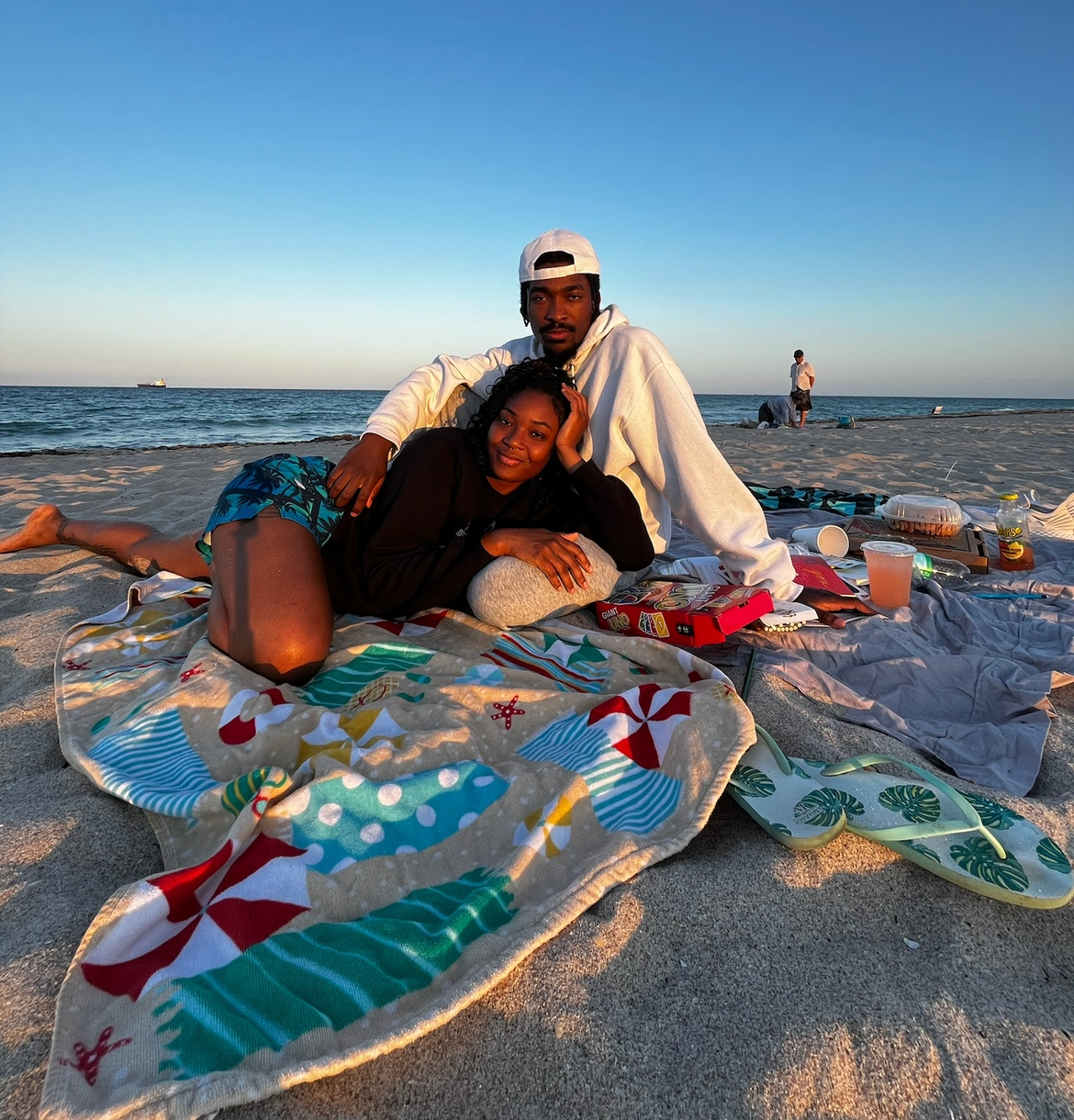 A couple relaxing together on a beach blanket at golden hour